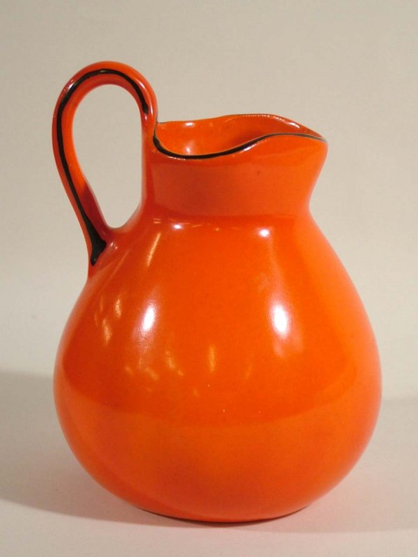 Czech Pottery Creamer: Czech Trade Mark Coronet Pottery tri-corner pitcher in bright orange with black trim stands 4.75" tall. Bottom marked "Trade Mark Coronet Czechoslovakia Registered". Lighter spots on the outside are f
