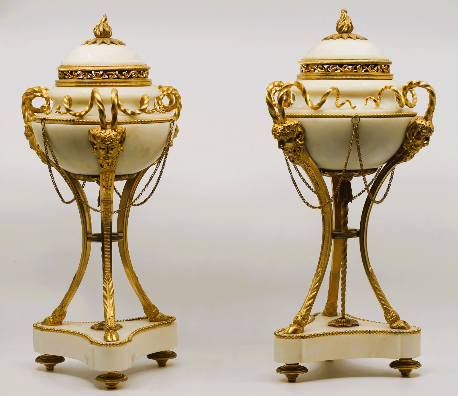 FRENCH D'ORE BRONZE & MARBLE CASSOLETTES, LATE 19TH/EARLY 20TH C: A pair of French d'ore bronze adorned white marble cassolettes. Each having a flame form finial, satyr form legs with spiral forms and a beaded base. Finely cast. H 15", DIA 6" All measurements