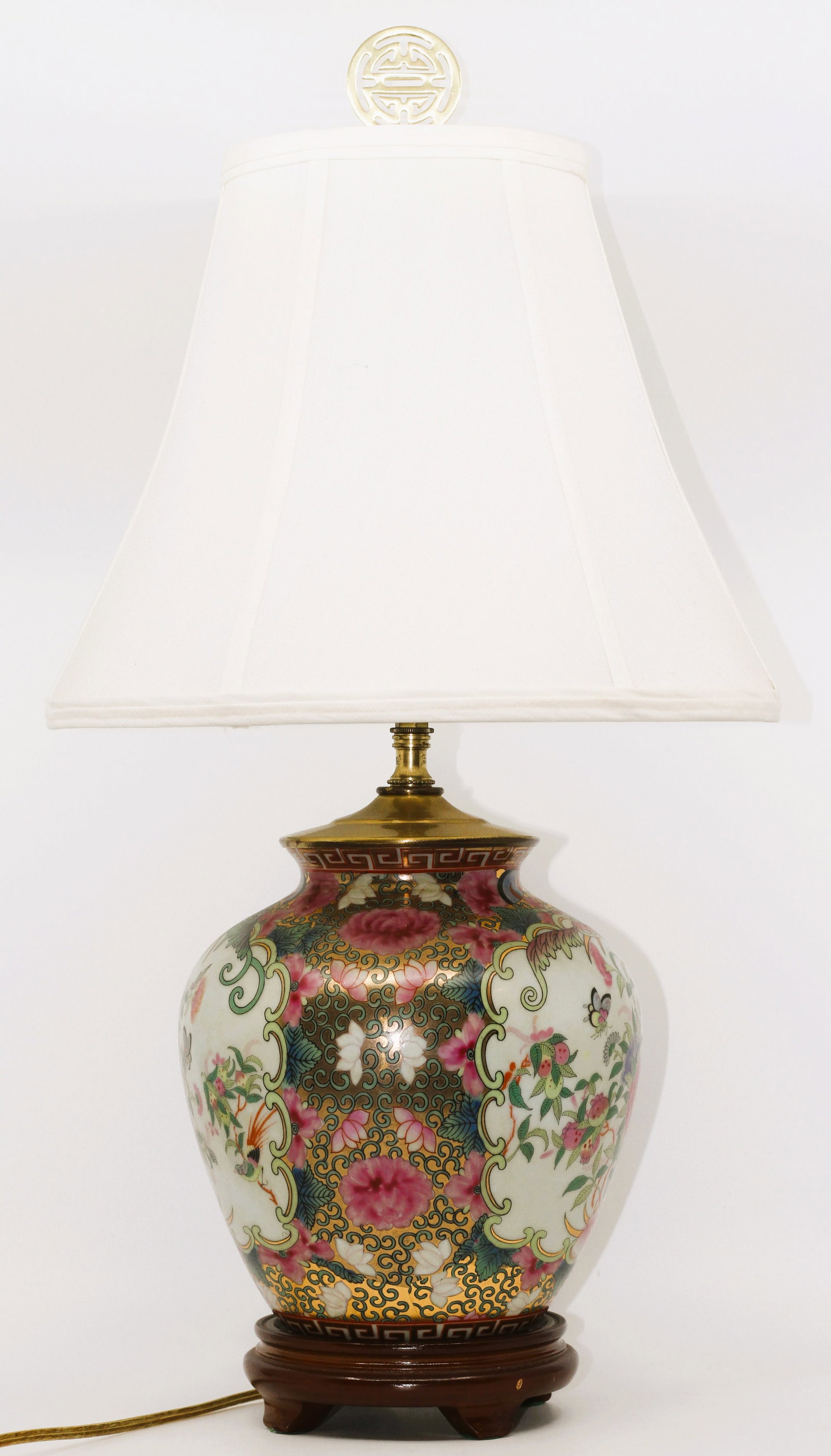 Chinese porcelain table lamp features a hand-painted floral Rose Medallion with gold accents: The porcelain jar displays intricate enamel painting featuring peonies, butterflies, and a bird surrounded by a gold-accented border.Base: The lamp sits on a carved dark wood stand