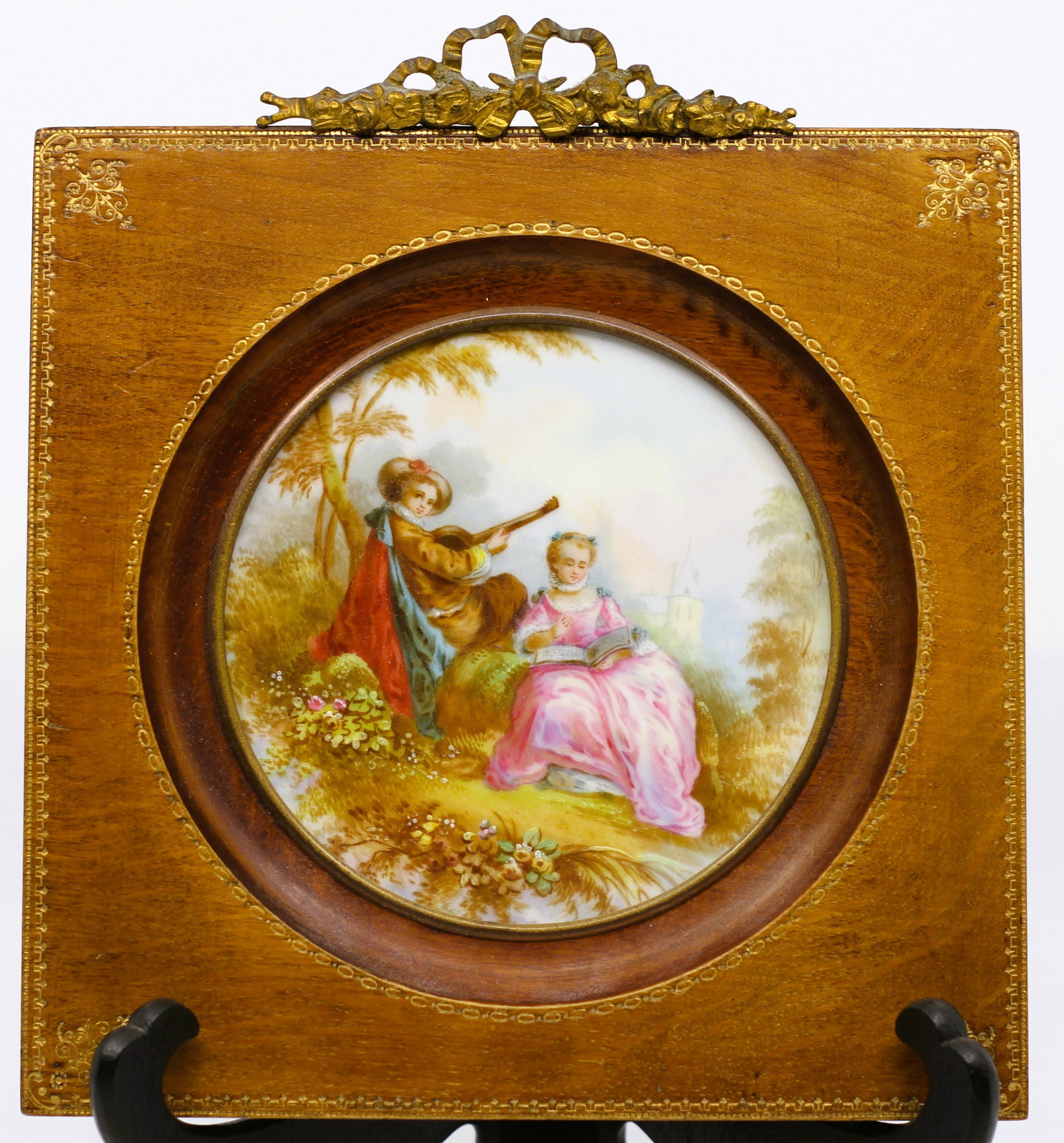 Antique French Porcelain Hand-Painted Plaque in Mahogany Veneer Frame, Romantic Pastoral Scene, c.: After Nicolas Lancret, proabably Late 19th-century French porcelain plaque depicting an elegant pastoral scene in the Rococo taste. The circular porcelain insert portrays a young woman seated outdoors