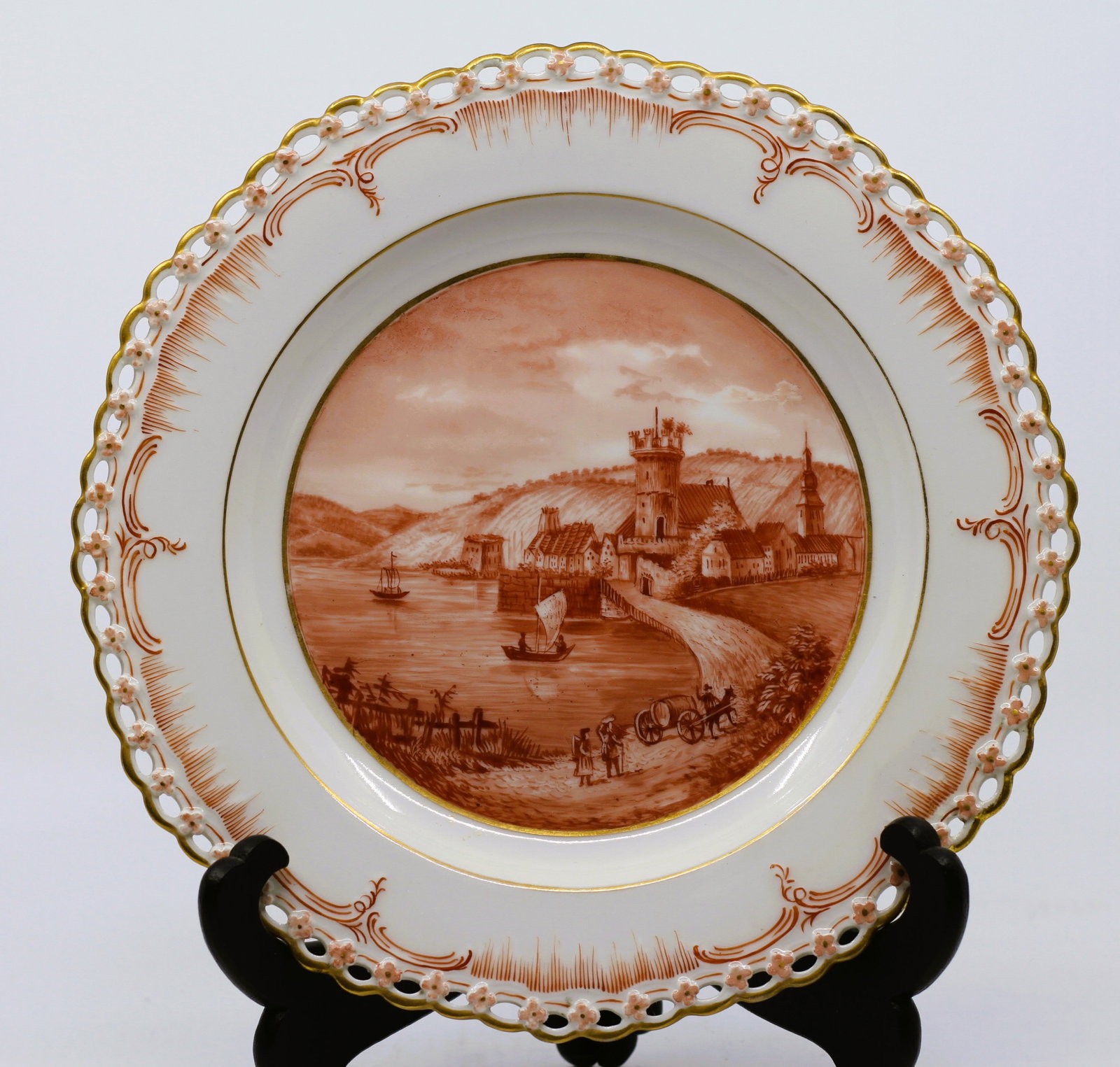 Fine Antique German/Austrian Porcelain Cabinet Plate, Hand-Painted Harbor Landscape: An elegant antique European porcelain cabinet plate featuring a finely hand-painted monochromatic sepia landscape depicting a fortified riverside town with towers, sailing vessels, and rolling hills. 