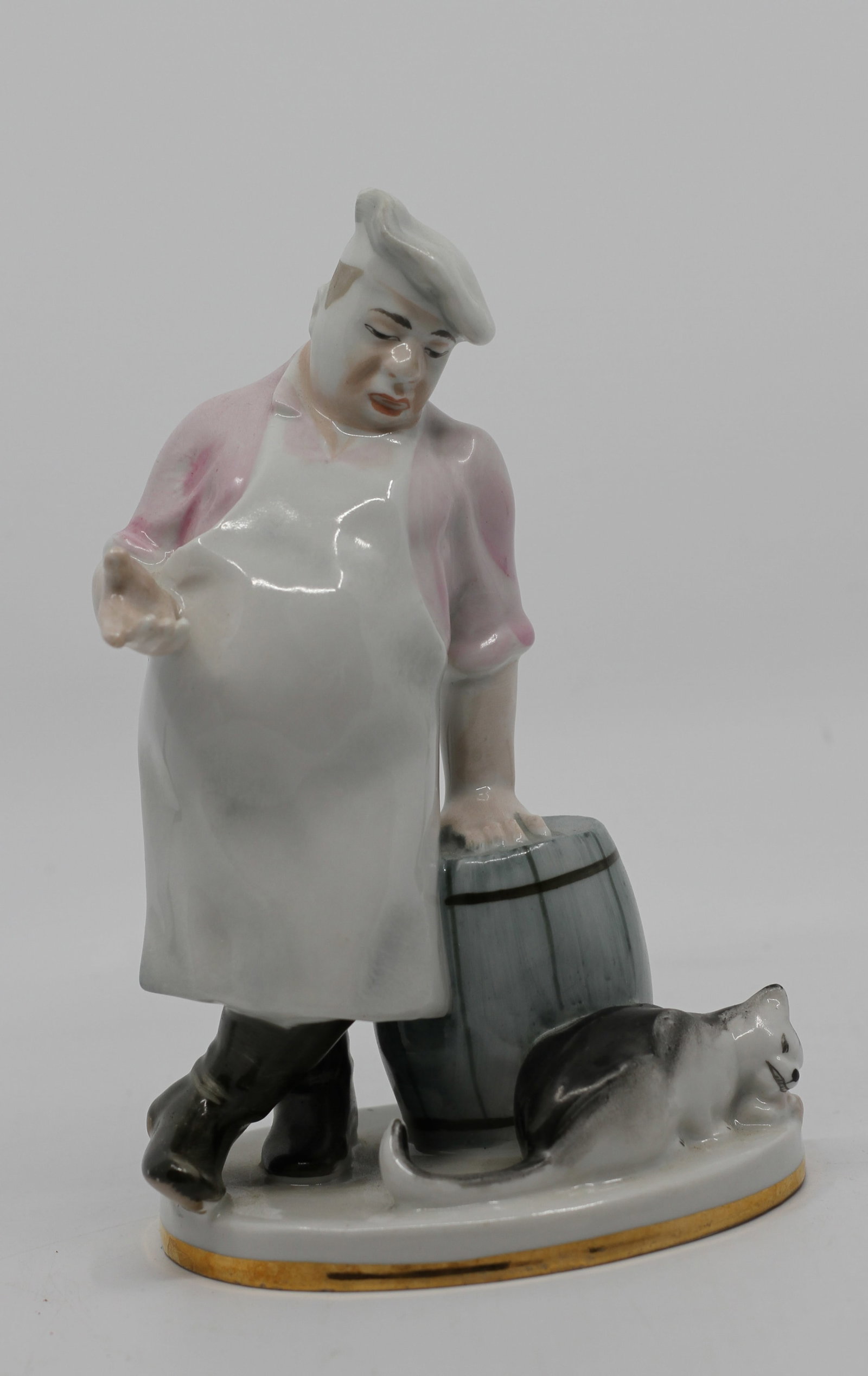 Antique Lomonosov LFZ Russian Porcelain Butcher Figure with Cat Figurine: Antique Lomonosov (LFZ) Russian porcelain figural group depicting a butcher standing beside a wooden barrel while extending one hand toward a curious cat at his feet. Beautifully hand-painted in soft 