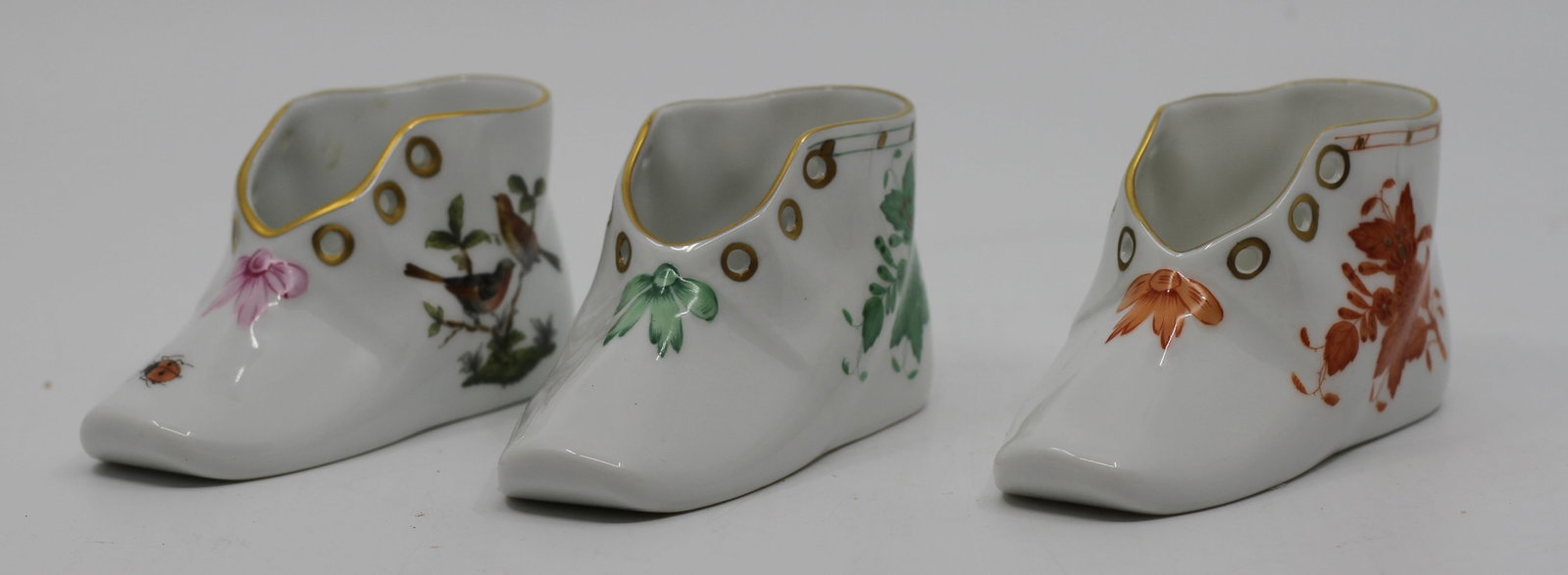 Set of Three Herend Hungary Hand-Painted Porcelain Miniature Shoe Figurines: Charming set of three Herend Hungary hand-painted porcelain miniature shoe figurines, each decorated in a different classic Herend pattern and accented with hand-applied gilt trim. The group includes 