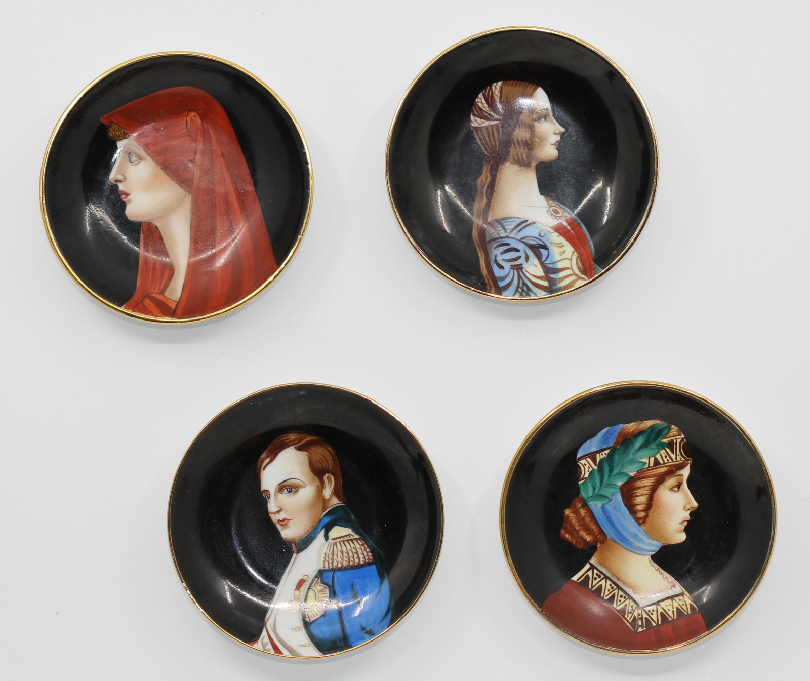 Set of Four Italian Hand-Painted Portrait Porcelain Cabinet Plates, After Piero Fornasetti: Elegant set of four Italian hand-painted porcelain cabinet plates featuring portrait studies inspired by Renaissance and historical figures in the style of Piero Fornasetti. The collection includes po