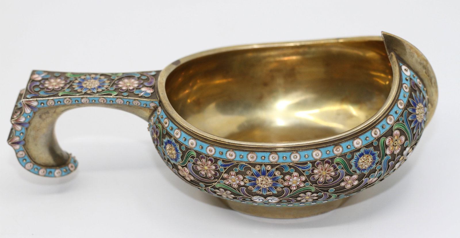 Russian Silver-Gilt Enamel Kovsh: Russian silver-gilt kovsh, circa 1900, richly decorated with shaded cloisonne enamel floral motifs in turquoise, blue, green, pink, and white. Features a gilt interior, raised prow, and angular handle