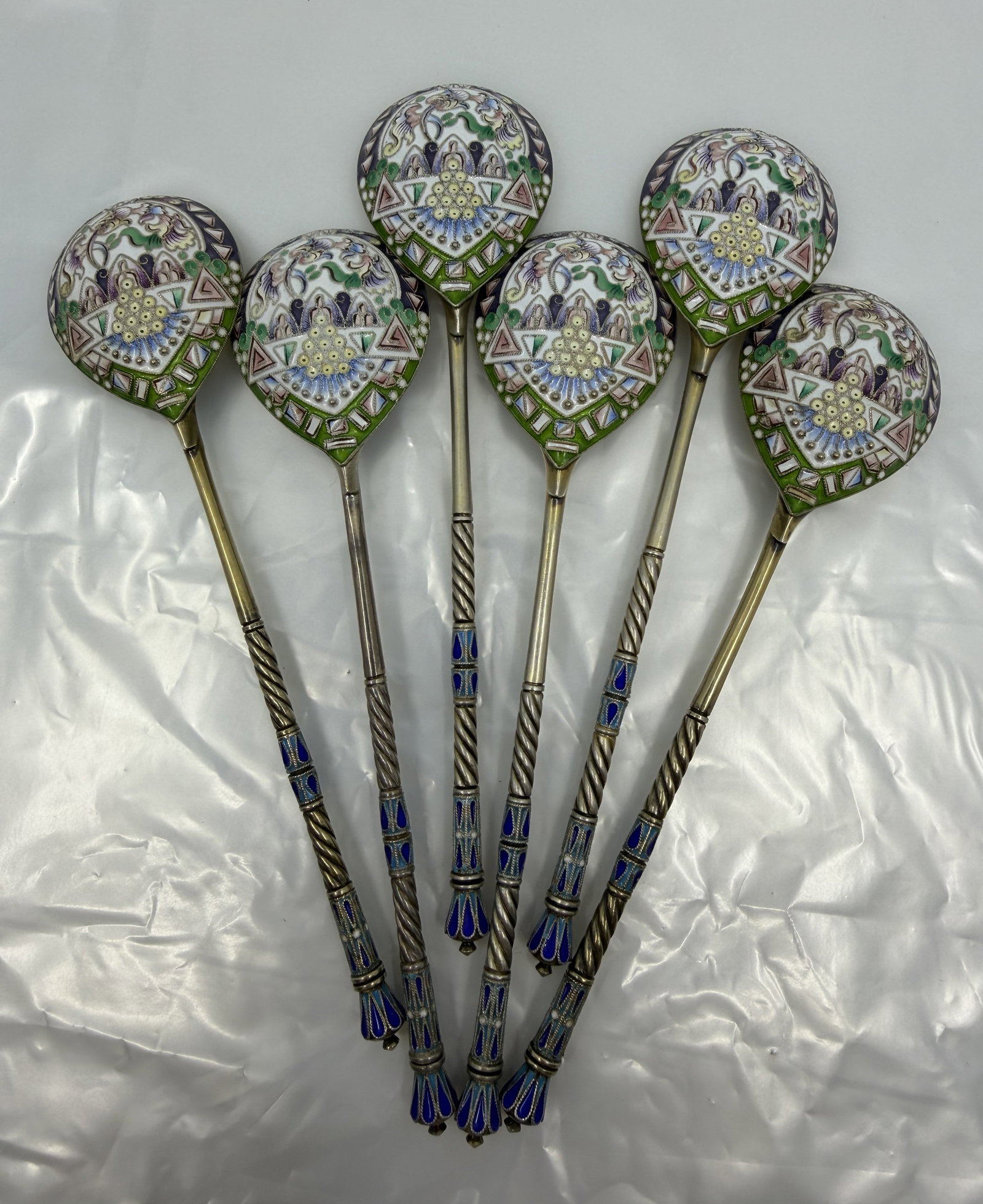 Set of Six Russian 88 Silver Enamel Spoons: Set of six large Russian silver-gilt serving spoons with elaborate multicolor cloisonne enamel decoration. Each features a teardrop-form bowl, twisted stem, blue enamel accents, and floral and geometr