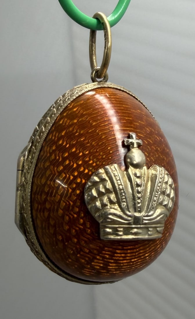 Russian 88 Silver Guilloche Enamel Egg Locket: Egg-form pendant locket with amber-brown guilloche enamel and applied silver Imperial-style crown emblem. Gilt interior with hinged construction and suspension ring. Bearing ?88? silver standard and a
