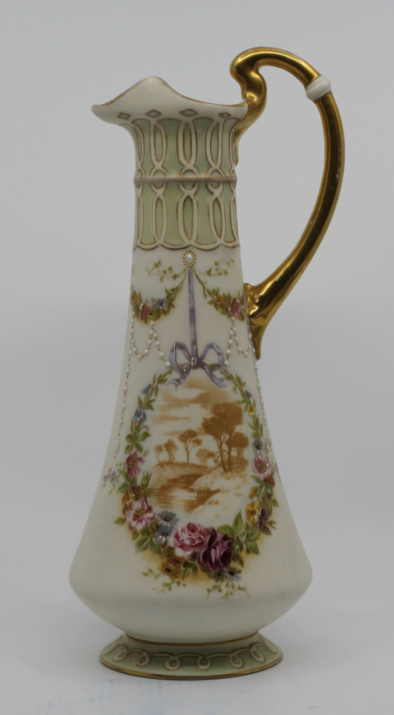 Austrian Porcelain Ewer with Landscape and Floral Decoration: Antique Austrian porcelain ewer of tall tapered form with flared spout and elongated gilt handle. Decorated with a sepia landscape medallion framed by hand-painted flowers, raised enamel pearl accents