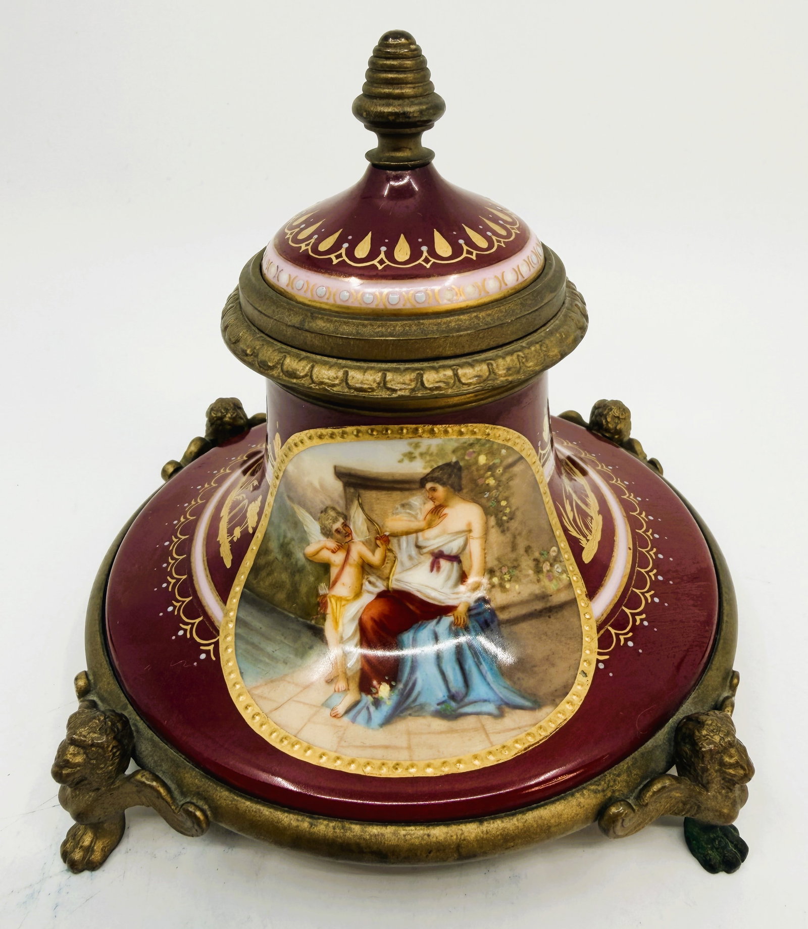 Antique Vienna Porcelain Inkwell with Gilt Bronze Mounts: Antique Vienna style porcelain inkwell with deep burgundy ground, gilt decoration, and hand painted classical figural scene with Cupid. Fitted with gilt bronze mounts, hinged cover, porcelain ink cup,