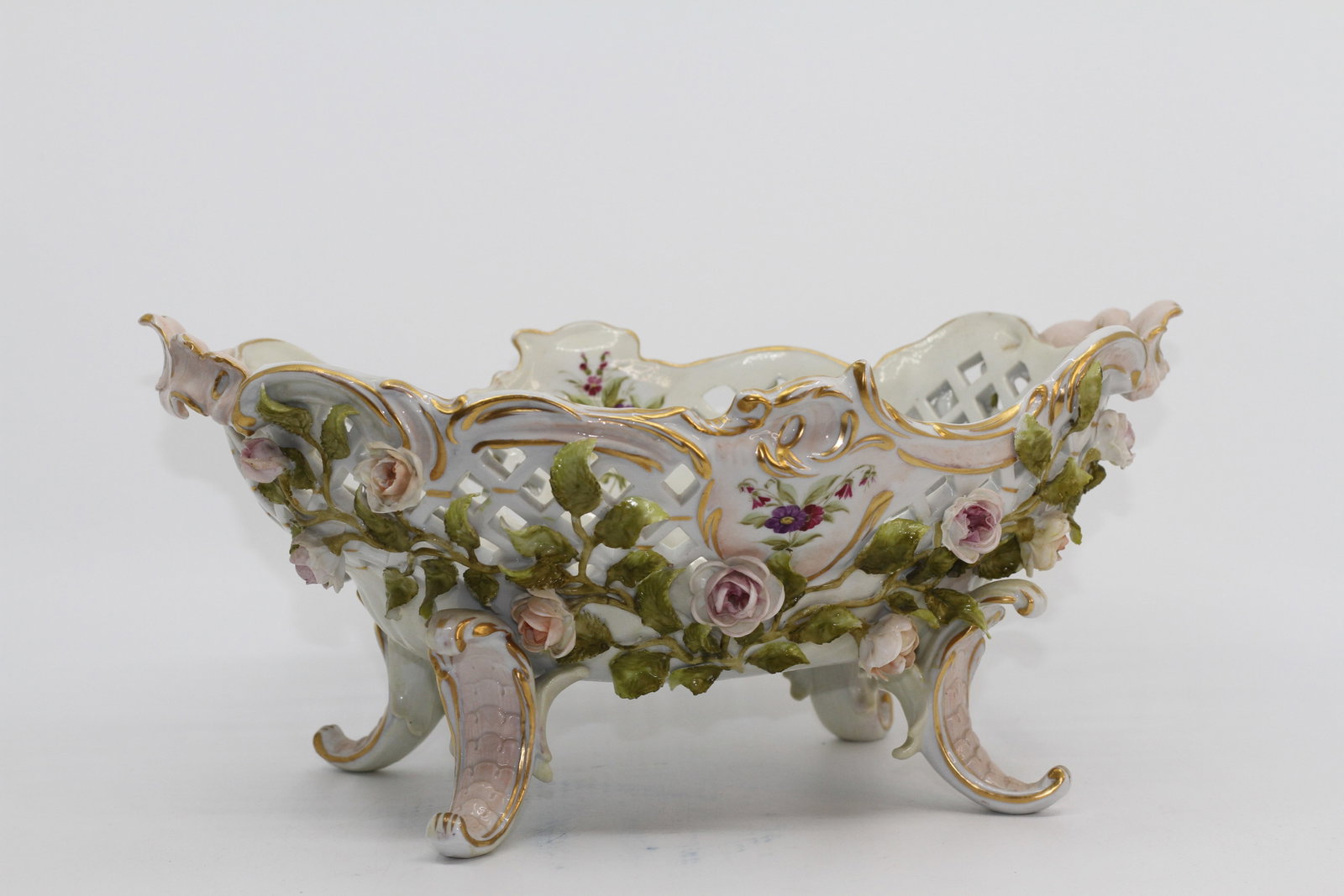 Antique Dresden Porcelain Floral Reticulated Centerpiece Bowl: Antique Continental porcelain centerpiece bowl in the Dresden style, with reticulated sides, applied porcelain roses and foliage, hand painted floral sprays, gilt rococo decoration, and four scrolling