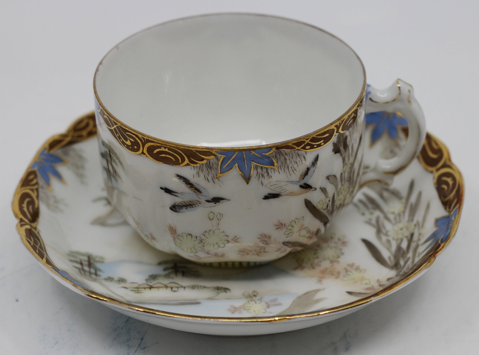 Gardner Russian Porcelain Cup and Saucer: Antique Russian porcelain cup and saucer by Gardner Moscow. Decorated with hand painted landscape, birds, flowers, blue accents and gilt ornament. Both pieces bear red Gardner factory marks.