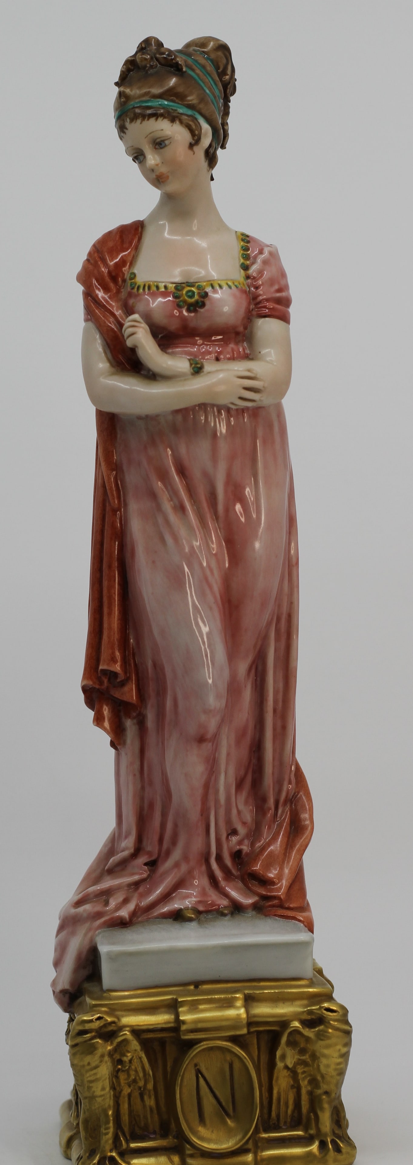 Capodimonte Empress Josephine Porcelain Figurine: Large porcelain figure depicting Empress Josephine in a pink Empire style gown with jeweled details and draped shawl. Raised on an ornate gilt architectural base with Napoleonic N medallion.