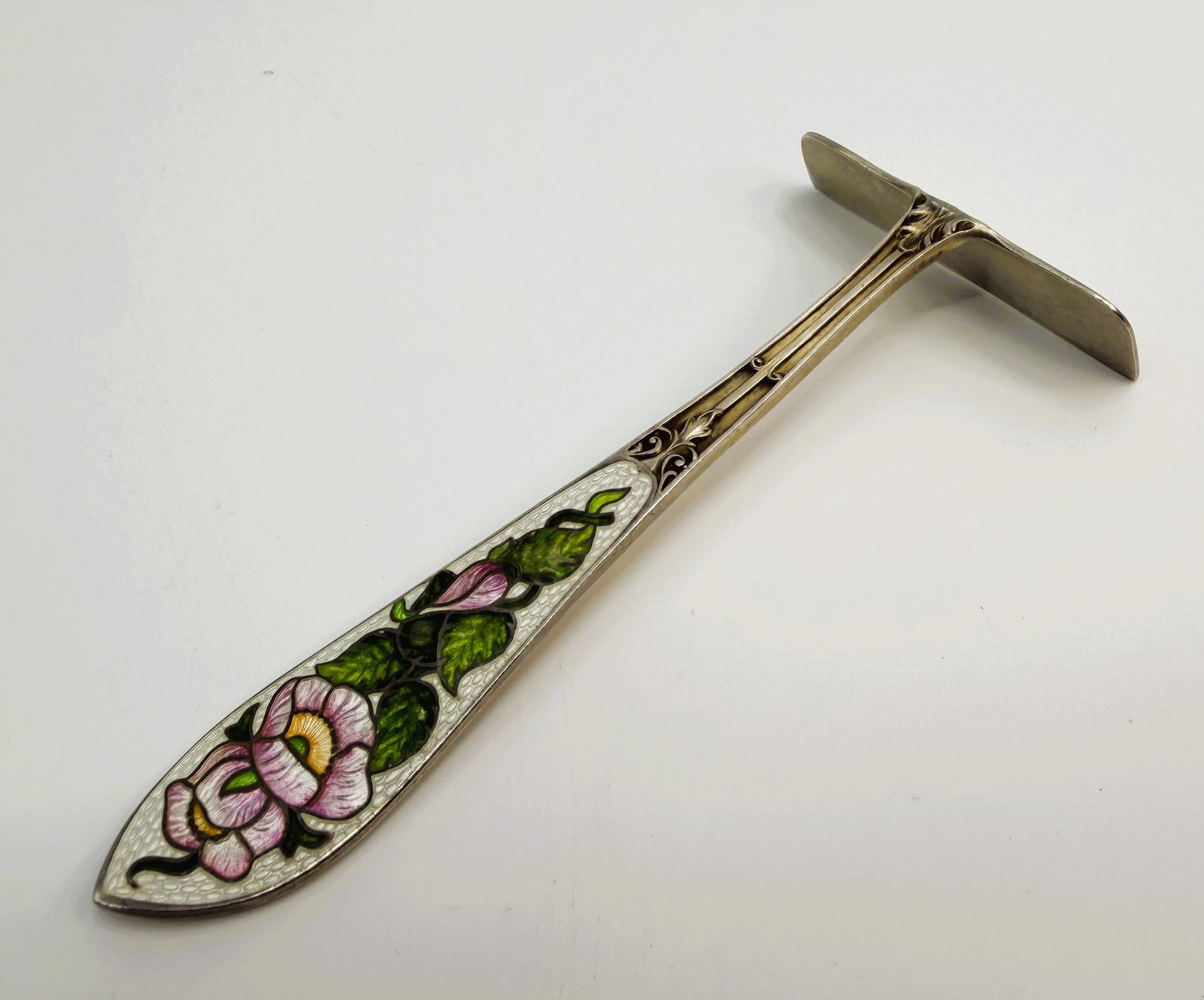 Antique Sterling Silver Enamel Baby Food Pusher: Circa 1920 sterling silver baby food pusher with floral enamel decoration in pink green and white. Ornate engraved handle. Marked Sterling on reverse. Length approximately 4 inches.