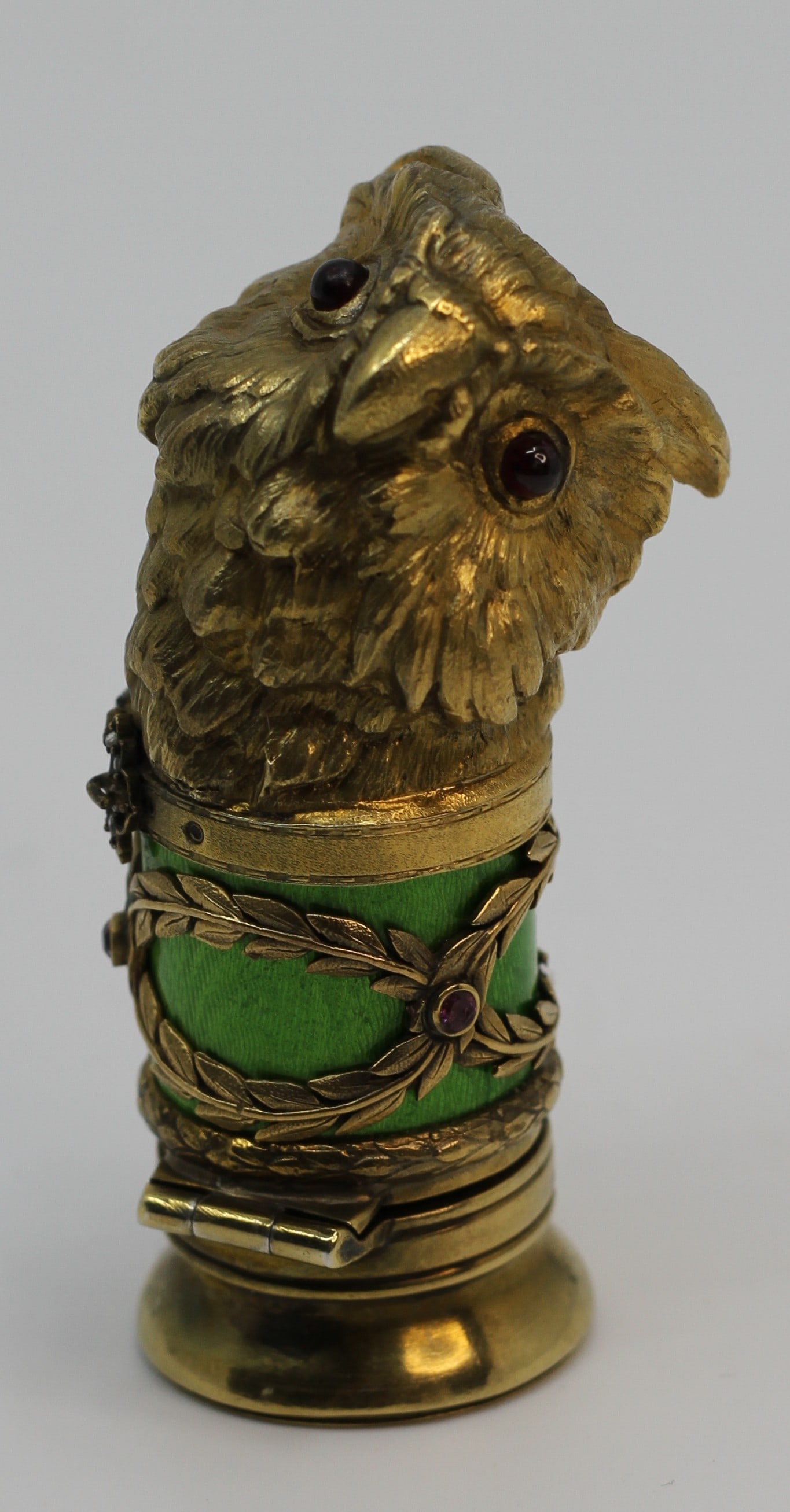 RUSSIAN GILT SILVER ENAMEL GEMSTONE OWL PILL BOX: A Russian gilt silver pill box with hinged lid. Owl head design. The eyes of the bird are set with ruby cabochons, the collar is garnished with diamonds. Green guilloche enamel body with ornamental
