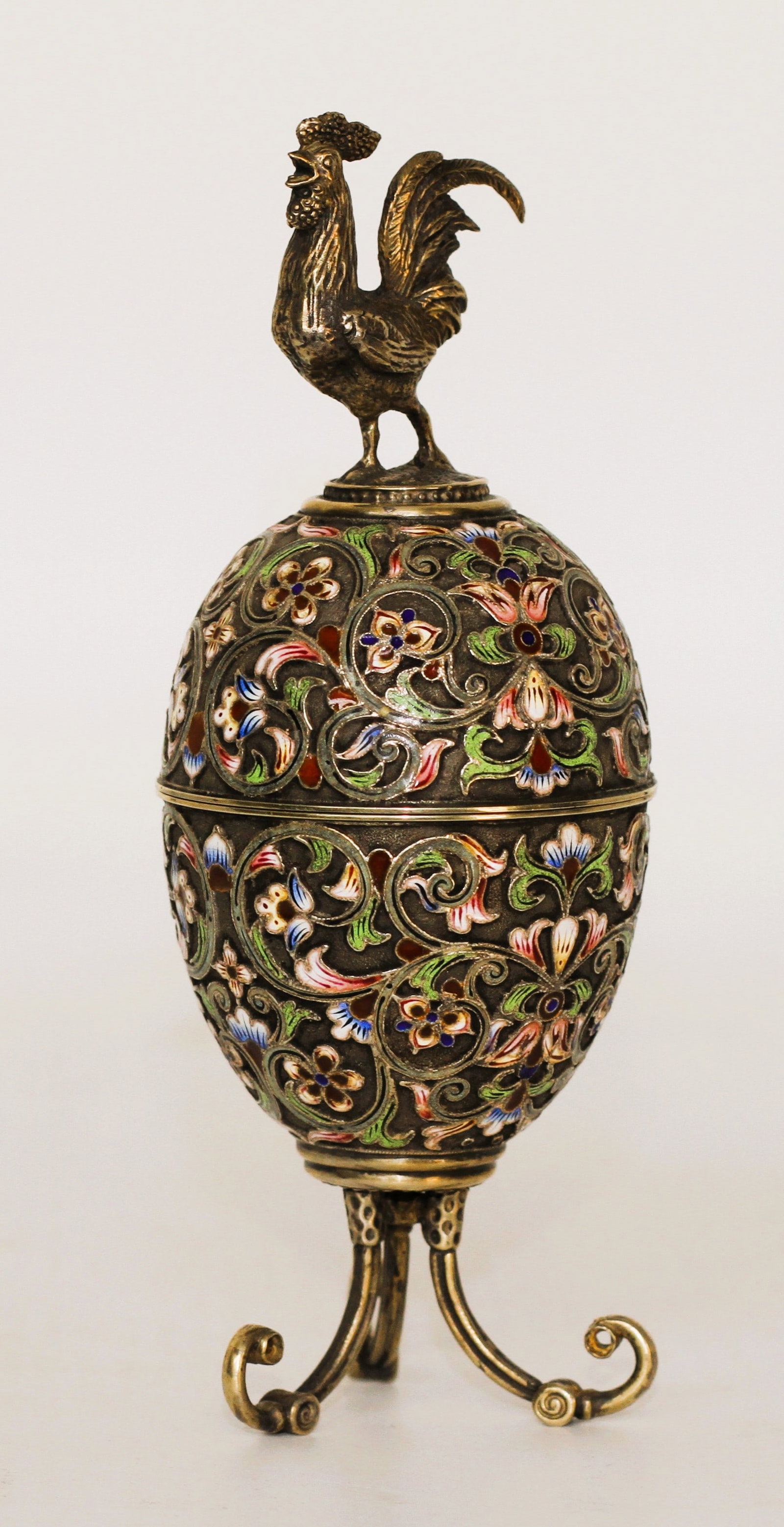 RUSSIAN 84 SILVER ENAMEL EGG CASE W COCK FIGURINE: Russian 84 silver and enamel egg trinket box and case. The egg is separated into two halves. The exterior is enameled with floral and foliage patterns in light green, cobalt blue, white, yellow, and r