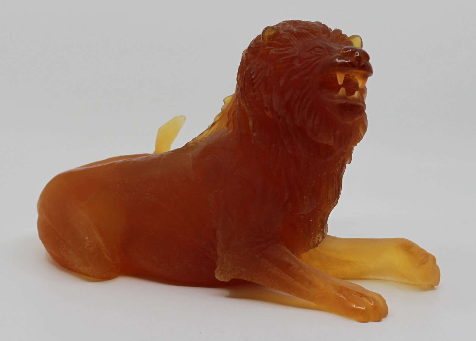 Daum France Amber Pate de Verre Grazing Lion Sculpture: Daum France pate de verre crystal sculpture depicting a reclining lion in rich amber and golden tones. Finely modeled with detailed mane, paws, and facial features.