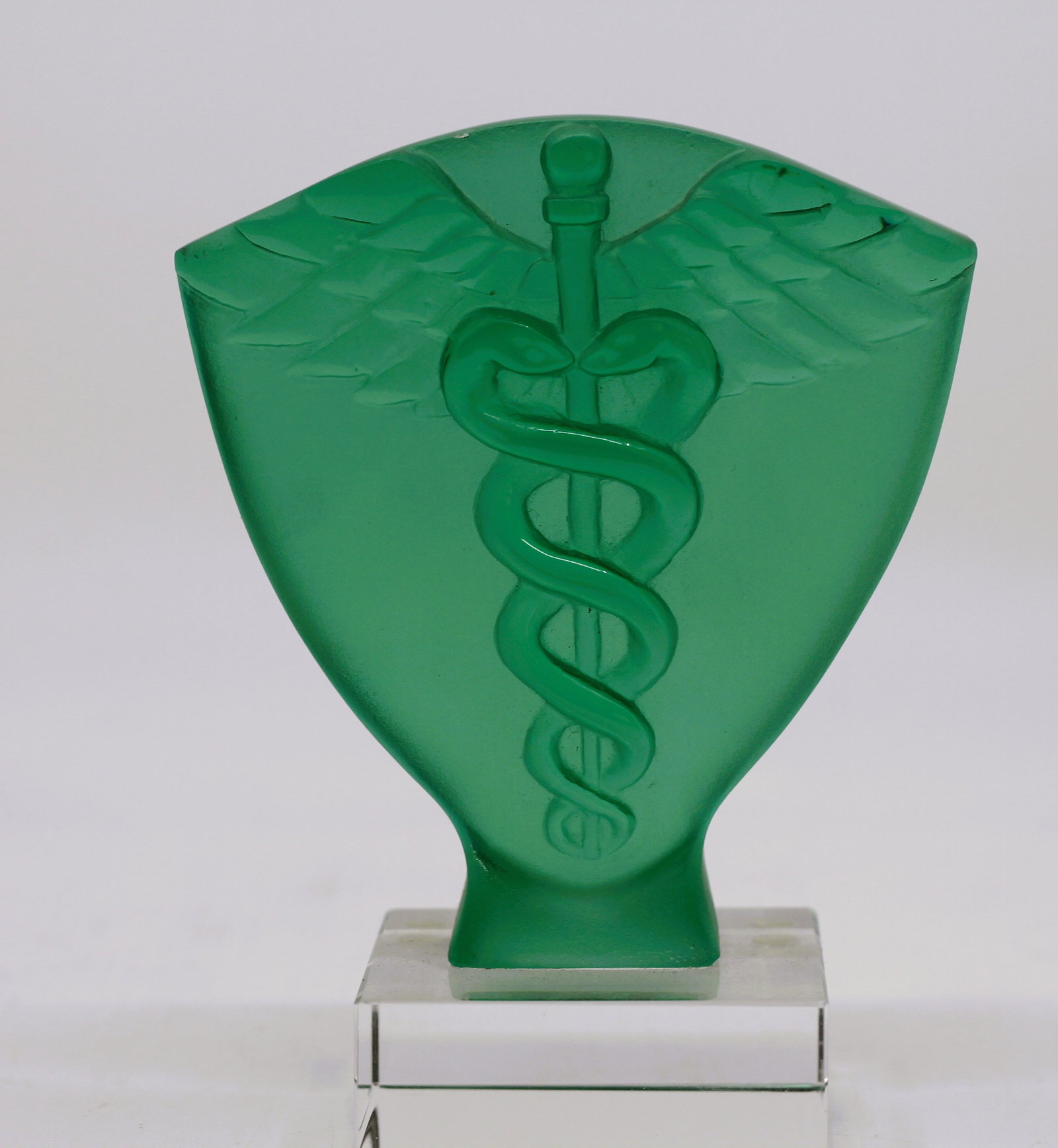 Daum France Green Pate de Cristal Caduceus Sculpture: Daum France green pate de cristal sculpture featuring a raised caduceus medical symbol with wings and entwined serpents. Mounted on a clear lucite base.