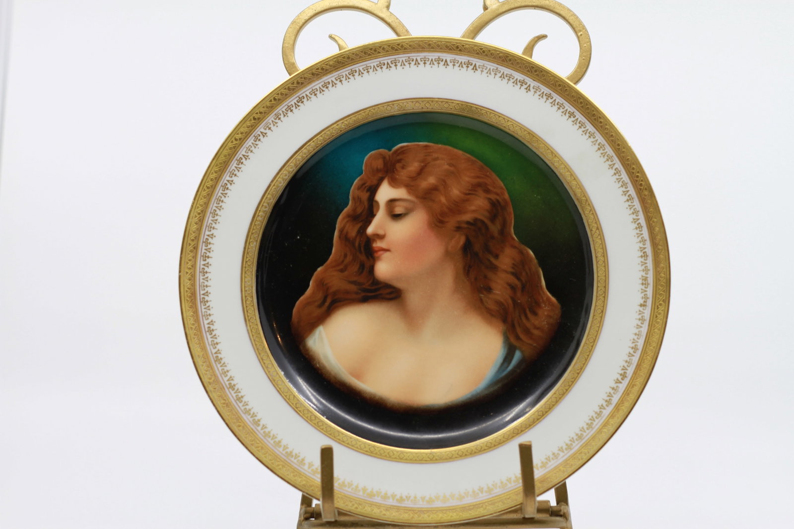 Antique Vienna Porcelain Portrait Plate: Fine porcelain cabinet plate featuring a hand painted portrait of a red haired young woman against a dark green and black ground. Wide white border with elaborate gilt decoration. Reverse with green f