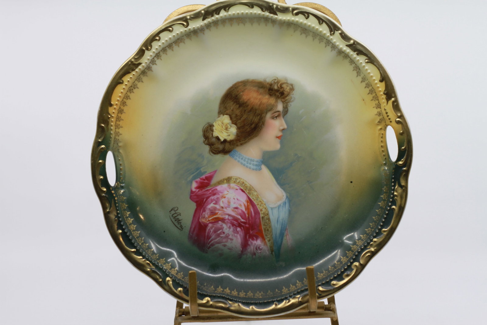 Antique Signed Porcelain Portrait Tray with Gilt Decoration: Antique porcelain handled tray featuring a finely painted portrait of a fashionable young woman with floral hair ornament, blue necklace and pink shawl. Signed R Lindner lower left. Decorated with gil