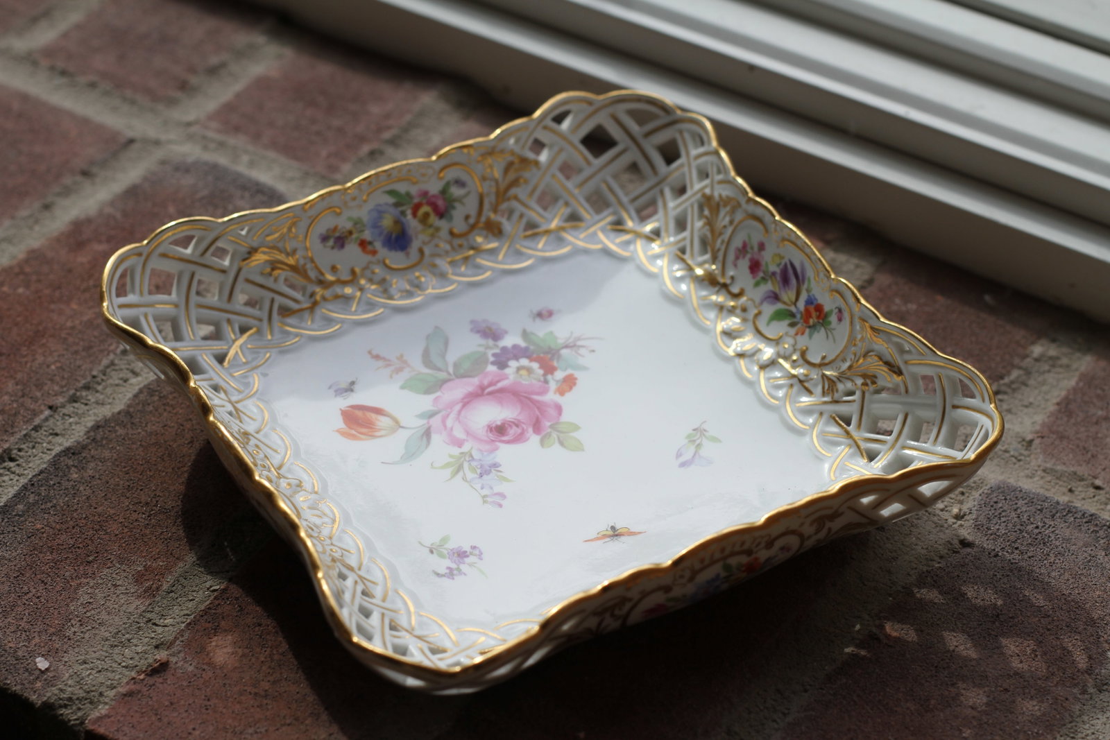Meissen Floral Reticulated Porcelain Serving Dish: Meissen porcelain square serving dish with pierced basket weave border, hand painted floral sprays, insects and extensive gilt decoration. Underside marked with blue crossed swords.