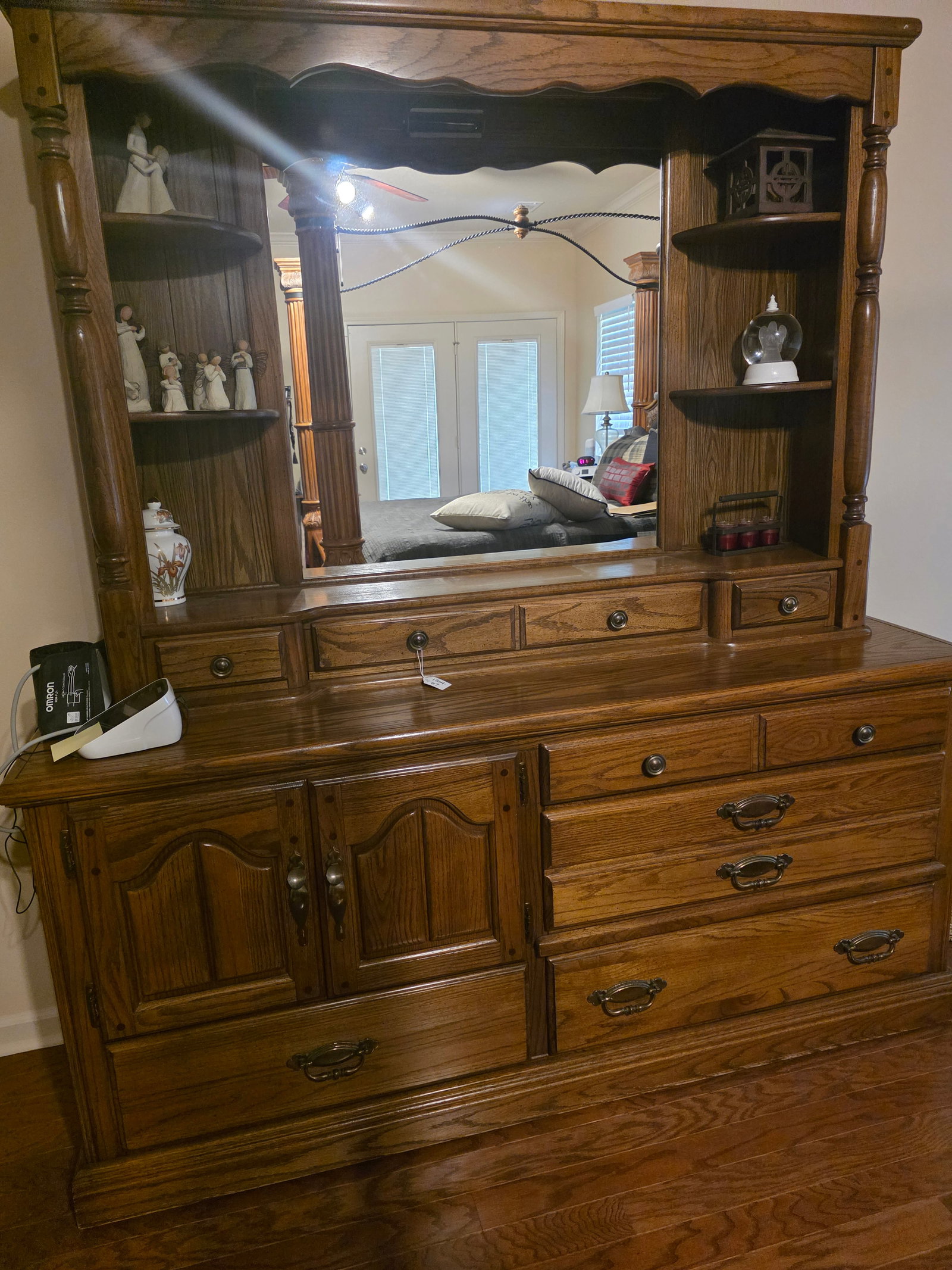 Large Oak dresser with Mirror Hutch: Solid oak or oak veneer construction with a medium-dark stain.Large attached mirror hutch with decorative shelves on both sides.Turned columns supporting the upper section.Combination of drawers and
