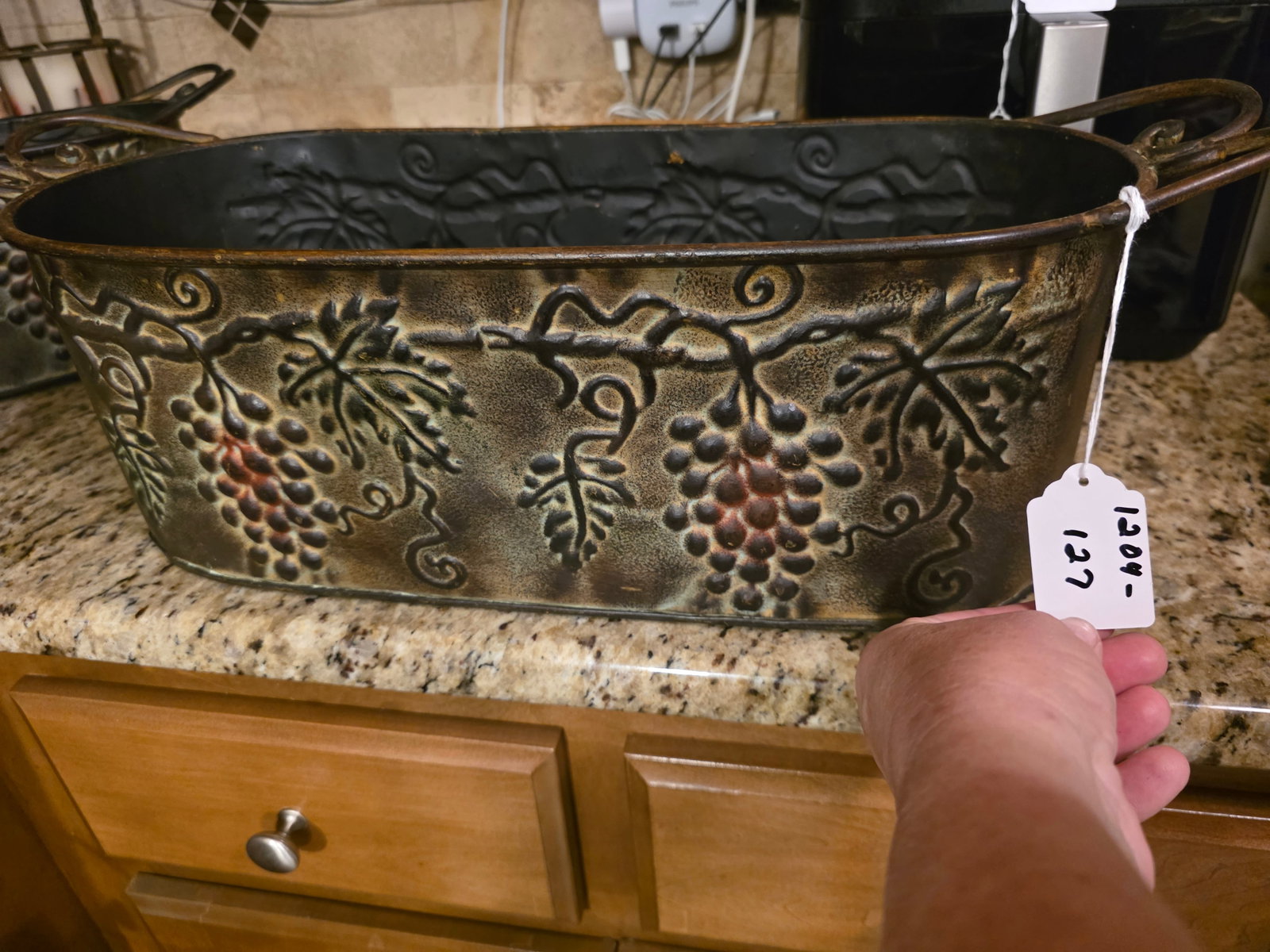 Large Decorative Centerpiece, planter or wine-themed serving tub: Stamped or embossed metal with a bronze-tone finishOval shaped with scroll handlesdecorated with raised grape clusters, leaves and vinesIntended for decor not heavy duty use