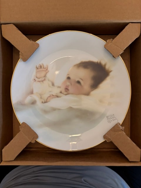 Bessie Pease Gutman, Awakening, Plate # 3536F: Collectible Plate, 1987, Dinner plate of painting of baby holding their hand up, Bundles of Joy Plate Collection, Fifth Issue,rim of plate is trimmed in 23K gold, distributed by The Heirloom Tradition
