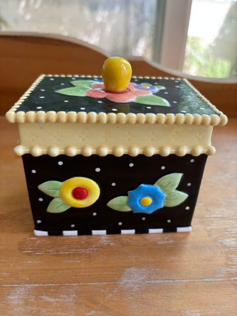 Vintage Mary Engelbreit Lidded Tea Trinket Box Container Flowers: The Vintage Mary Engelbreit Lidded Tea or trinket Box Container with Flowers is a charming decorative collectible piece that adds a touch of nostalgia and whimsy to any space. This container is perfec
