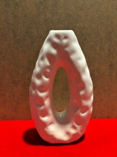 White texted vase, oblong shape: This bottom portion of the vase is matte. The rest of the white vase is glossy and features a distinct organic, textured surface and a hollow center.