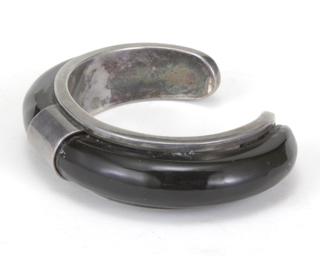 STYLE OF GEORG JENSEN, AN EBONIZED WOOD & SILVER BANGLE: STYLE OF GEORG JENSEN, AN EBONIZED WOOD & SILVER BANGLE. Designed by Andreas Mikkelsen Stamped: 925 Illegible 69.5 grams (gross) Width: 18-20mm (avg) Inner circumference: 6.5