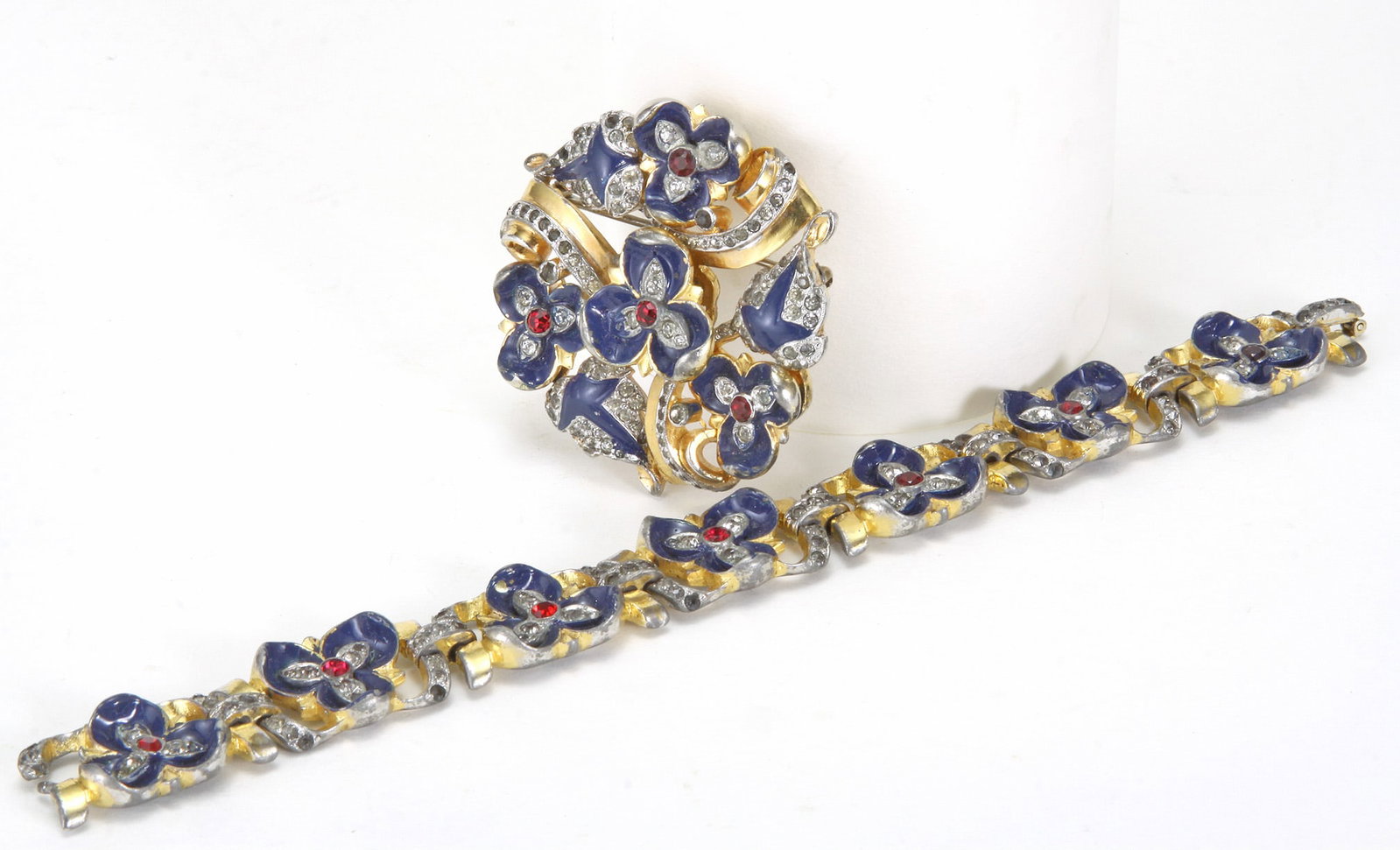 1930 MAZER BROS. ENAMEL & RHINSTONE BROOCH AND BRACELET SET: LOT OF 2 MAZER BROS. ENAMEL & RHINESTONE BROOCH AND BRACELET SET. Features a vibrant floral bouquet design with deep blue enamel and red rhinestone centers, and white rhinestone accents. Brand: Ma