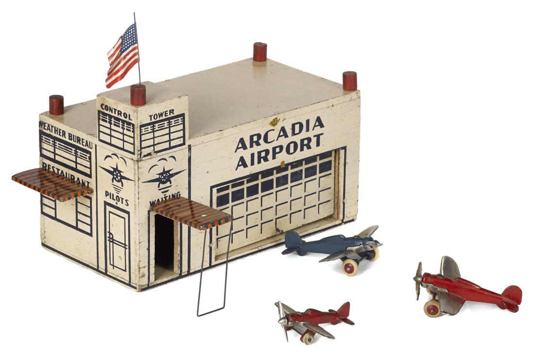 Arcade painted wood Arcadia Airport terminal with tin: Arcade painted wood Arcadia Airport terminal with tin awnings and a flag, together with three cast iron and nickel-plated airplanes, 11'' h., 12 1/4'' w.