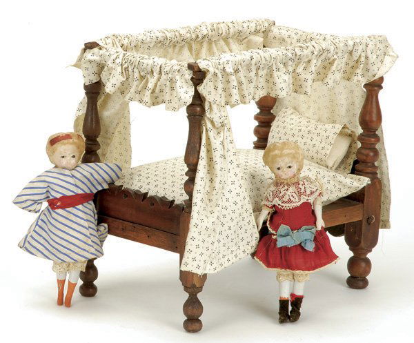 Lot: 2 Small Pumpkin Head Dolls and Bed: includes a pair of German pumpkin head wax over paper mache dolls with glass eyes, cloth bodies and wooden limbs, both wearing vintage clothes, also included an antique carved walnut tester bed Size: