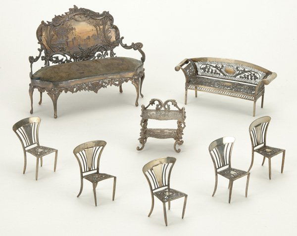 Lot: Silver Miniatures: an assortment of silver parlor pieces including two settees (upholstery worn), five chairs and a small etagere with embossed panels., largest 7" l.