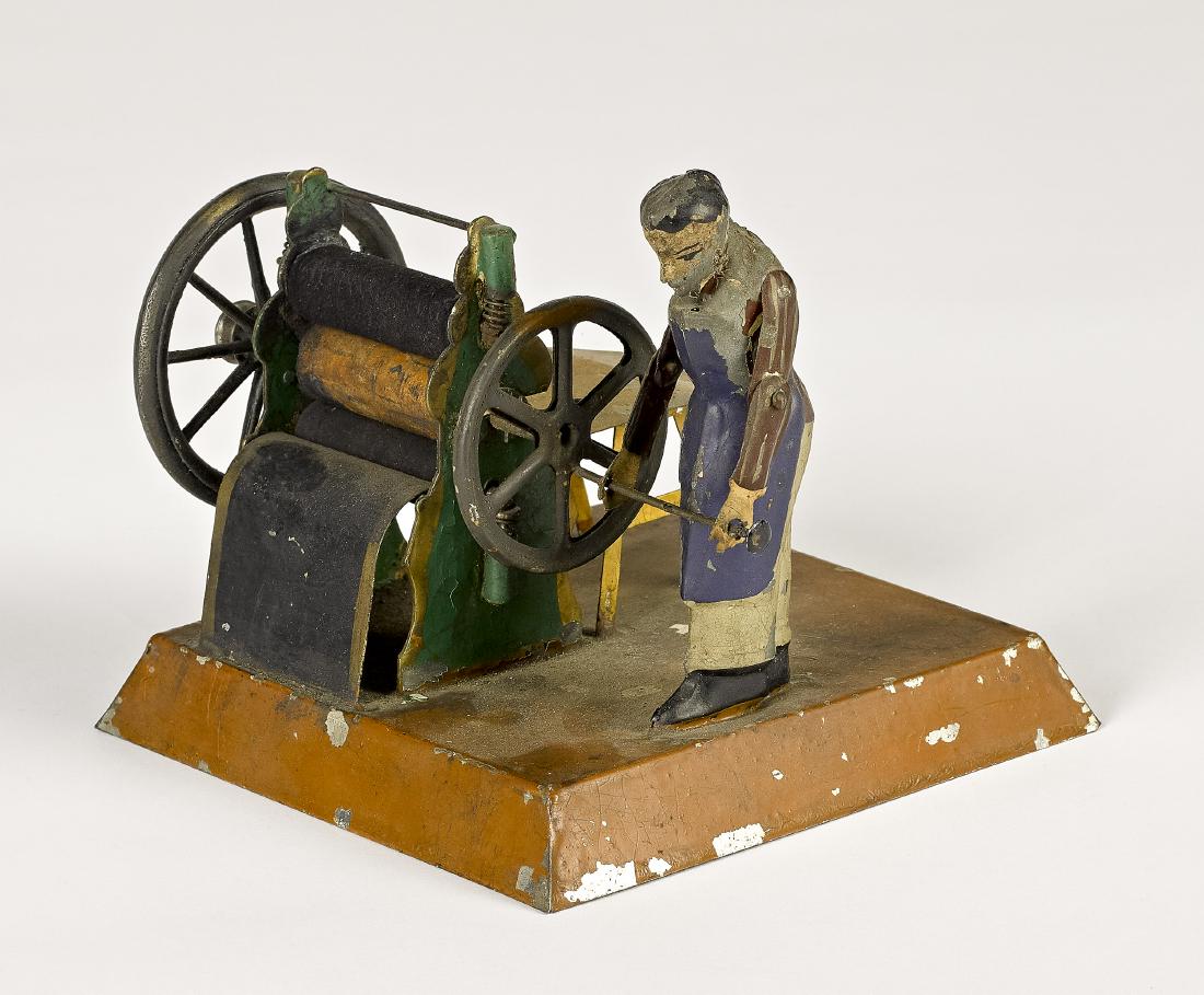 Falk printing press steam toy accessory: Falk painted tin printing press steam toy accessory, with cast iron drive wheels, 5 1/2'' h., 5'' w., 6 1/2'' d. Provenance: Morton A. Hirschberg Steam Toy Collection.