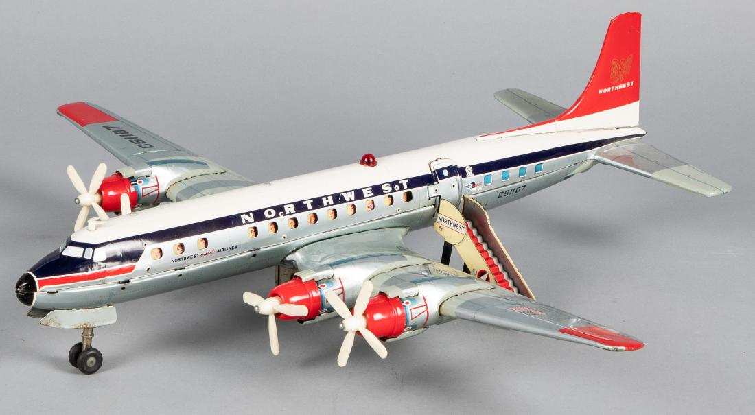 Japanese Cragstan tin lithograph friciton airplane: Japanese Cragstan tin lithograph battery operated Northwest Orient Airlines friction airplane, having an opening door with stewardess and steps, 23 1/2'' wingspan. Provenance: Estate of Jonathan Barro