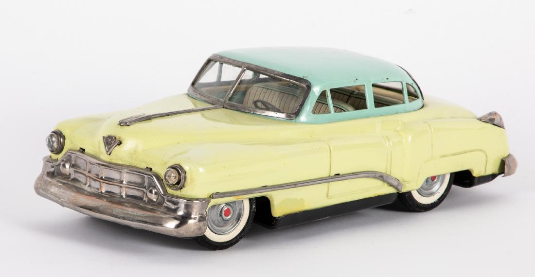 Japanese tin battery operated Cadillac: Japanese tin battery operated Cadillac, with two-tone paint and headlights, 13 1/2''. Provenance: Estate of Jonathan Barrow, Los Angeles, California.
