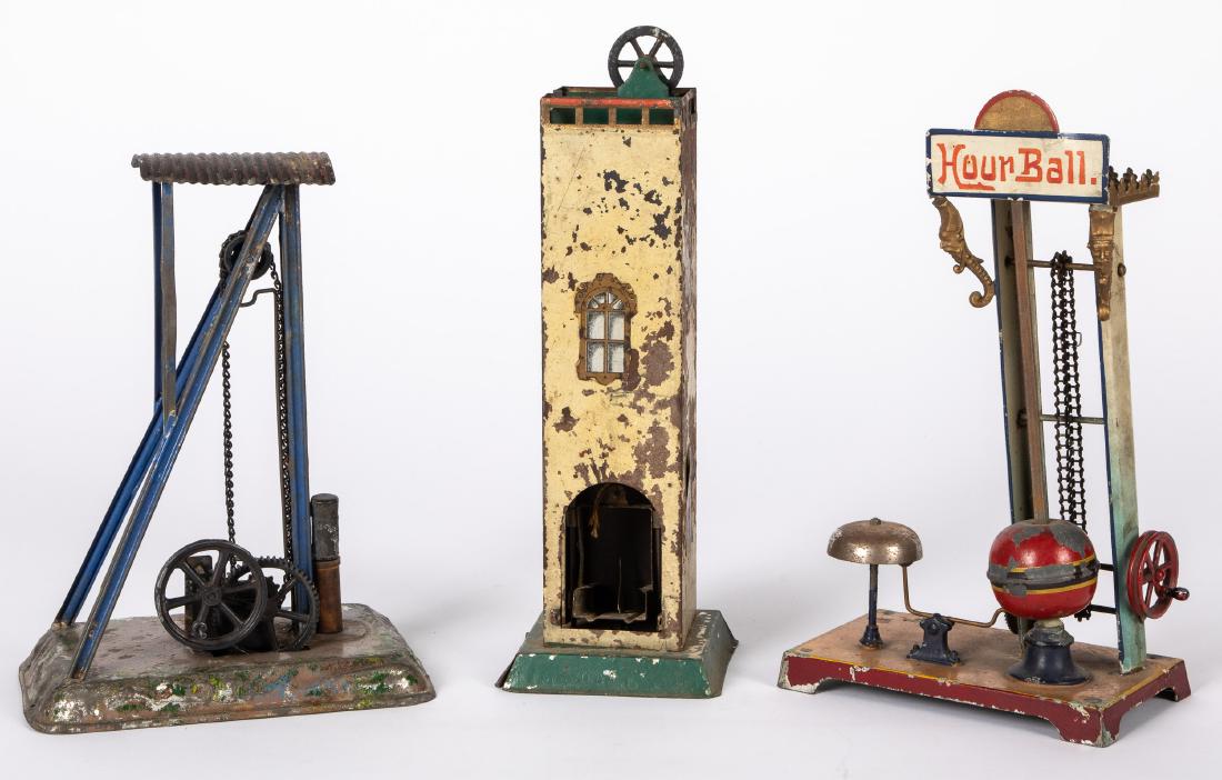 Three painted tin steam toy accessories: Three painted tin steam toy accessories, to include an elevator, an Hour Ball drop with bell and a Bing drop press, tallest - 12''. Provenance: Morton A. Hirschberg.