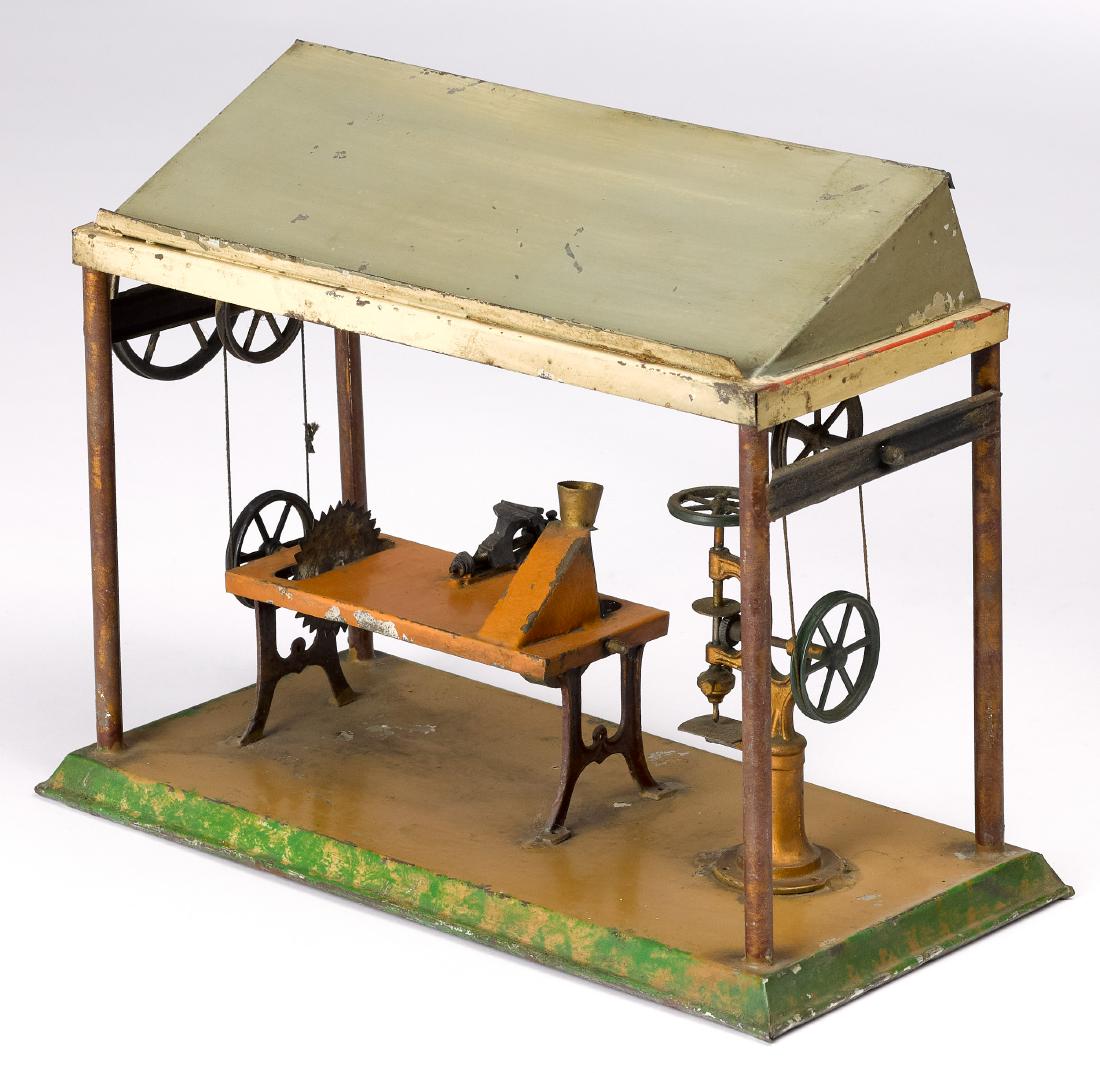Plank painted tin machine shop steam toy accessory: Plank painted tin machine shop steam toy accessory, with a drill press, a grinder, a vise and a table saw, 9'' h., 11 1/2'' w. Pictured in Morton A. Hirschberg Steam Toys - A Symphony in Motion, page 