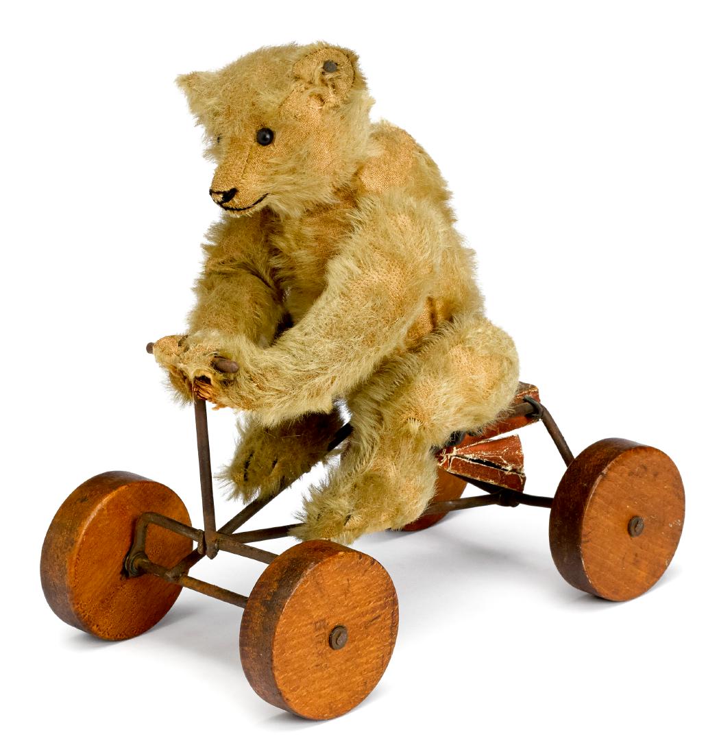 Steiff mohair teddy bear on Irish mail pull toy: Steiff ''Record'' mohair teddy bear on Irish mail pull toy, ca. 1915, with long trailing ''f'' button in ear, hump, elongated limbs, and squeaker, with wood wheels also stamped Steiff, 10'' h., 9'' l.