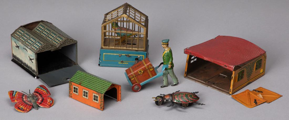 Tin lithograph penny toys: Tin lithograph penny toys, to include a German singing bird in a cage wind-up, 3 1/2'' h., a beetle, a porter with luggage, and two airplane hangers, together with a German tin lithograph butterfly to