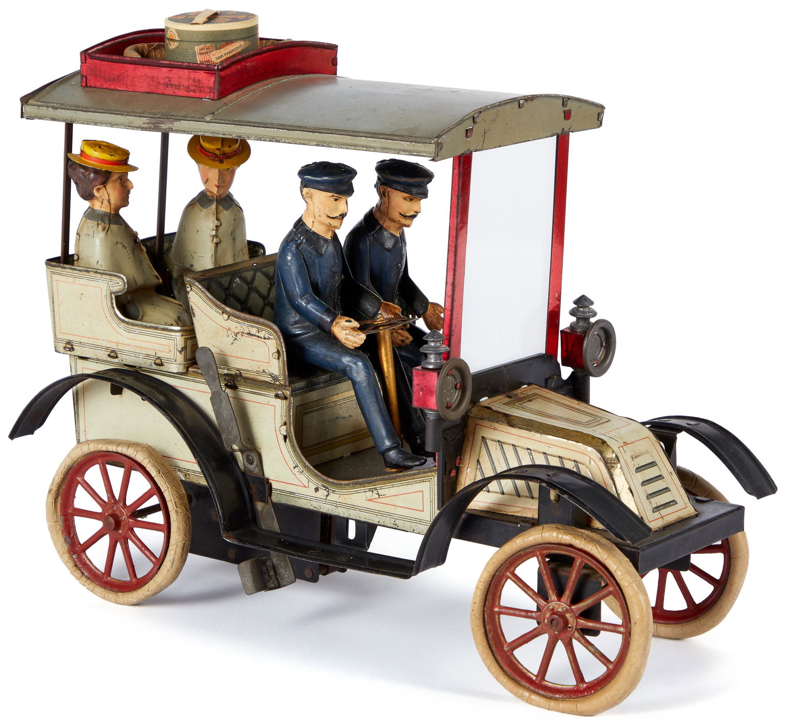 Carette tinplate clockwork touring car: Carette tinplate clockwork touring car, with two gentlemen and two women passengers, detachable driving lamps, hat box, and spare tire stored in roof top luggage rack, 12 1/8'' l.