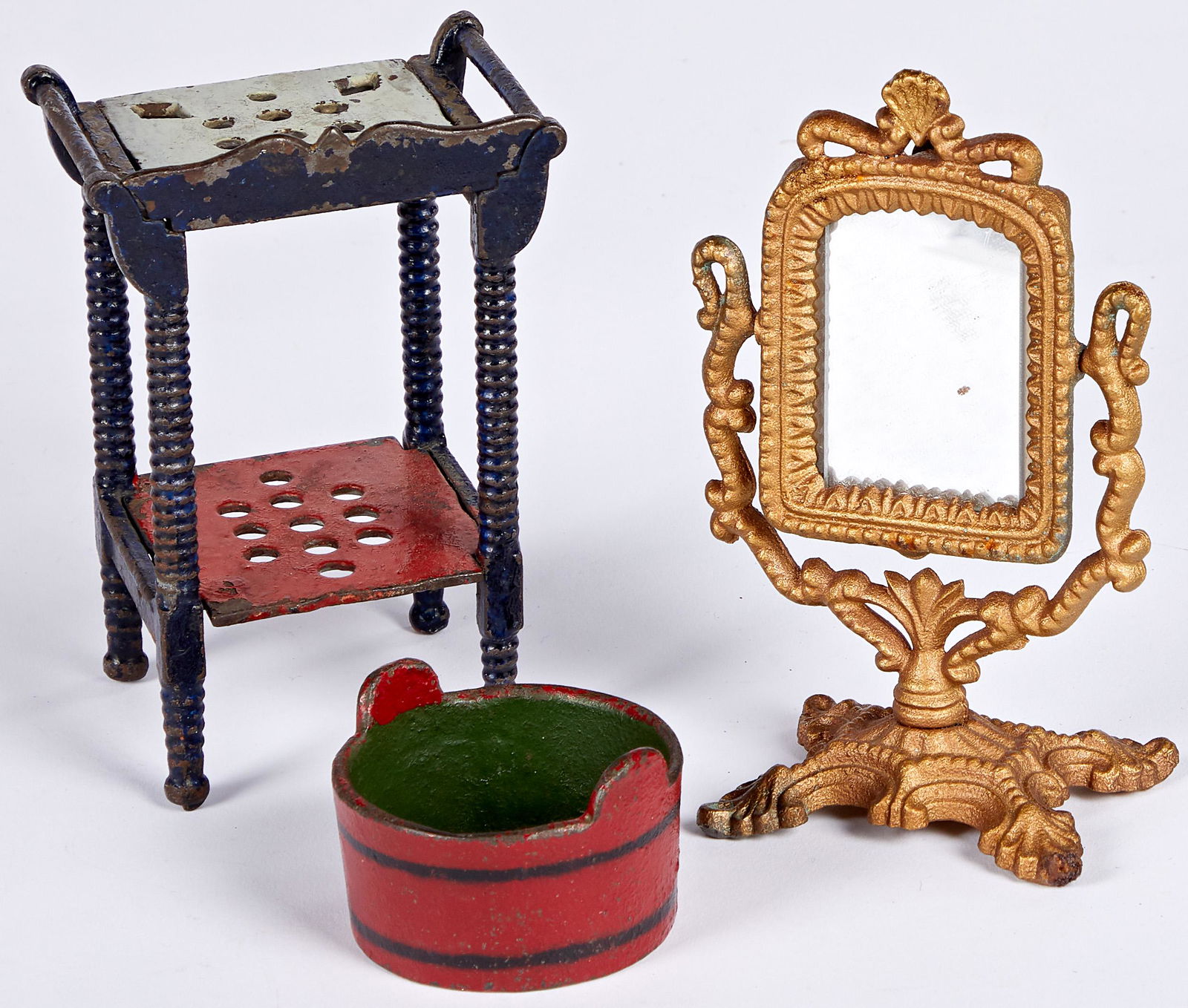 J. & E. Stevens cast iron dollhouse furniture: Three pieces of J. & E. Stevens cast iron dollhouse furniture, to include a washstand, 5'' h., a gilt dresser mirror, 5 1/2'' h. and a reproduction wash tub, 1 1/2'' h. Provenance: Collection of Bill