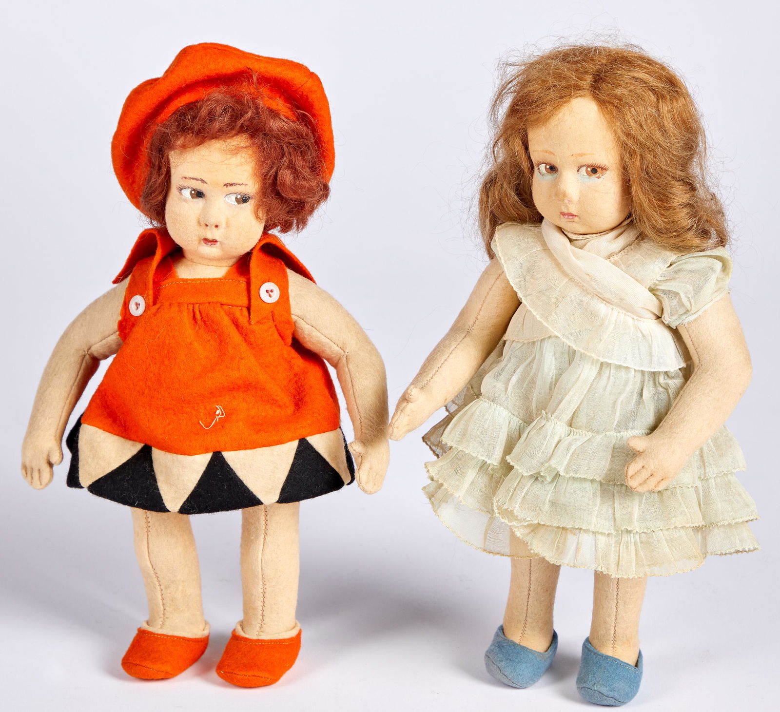 Two Lenci child felt dolls: Two Lenci child felt dolls, with stuffed torsos, painted side glancing eyes, closed mouths, and mitten hands with defined fingers, the girl having under eye shadow in an organdy dress, the other in a