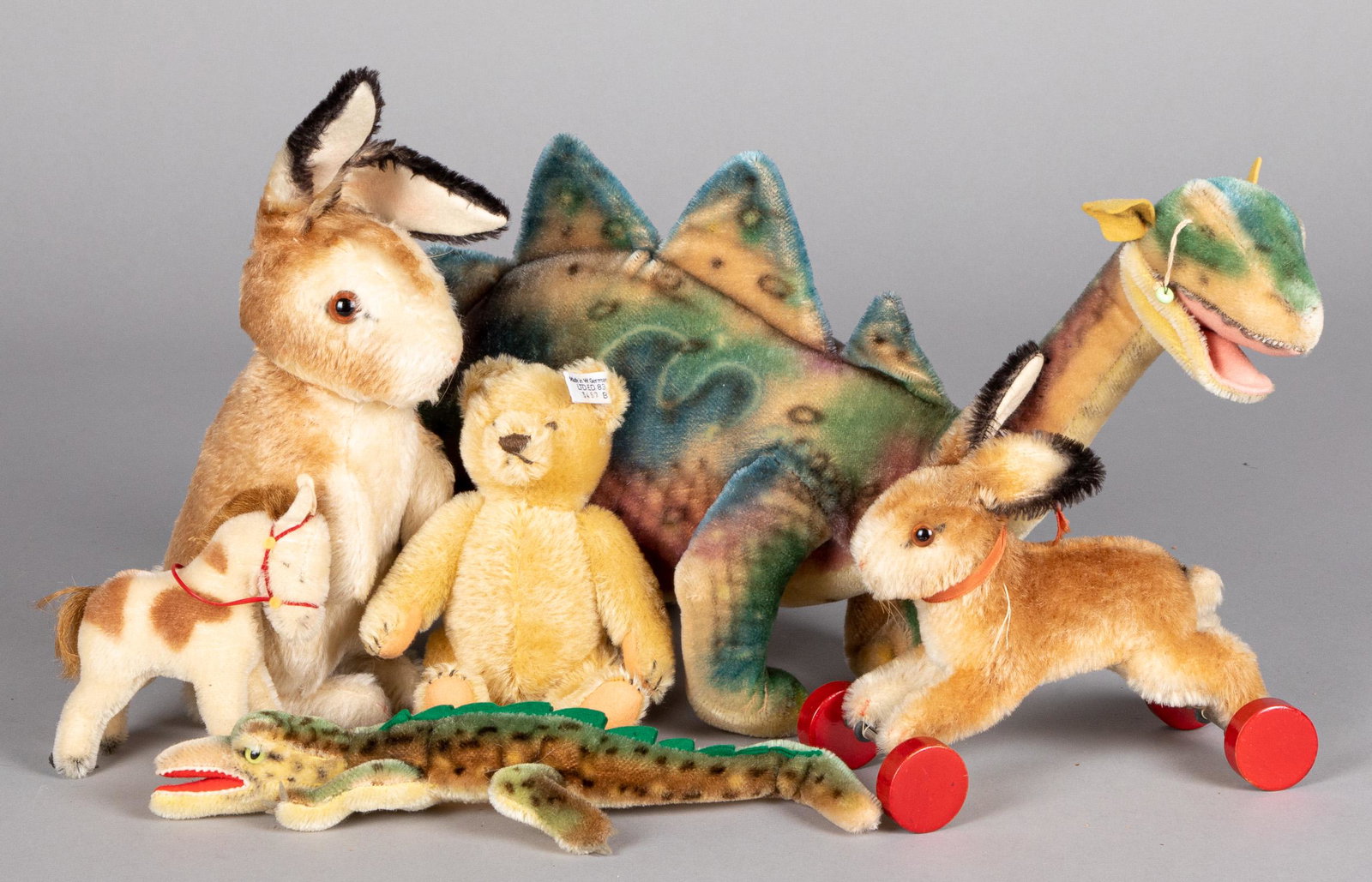 Group of vintage Steiff and plush animals: Group of vintage Steiff and plush animals, to include a dinosaur, a rabbit pull toy, a crocodile, a pony, and a seated rabbit, together with a contemporary Steiff teddy bear, dinosaur - 28'' l.