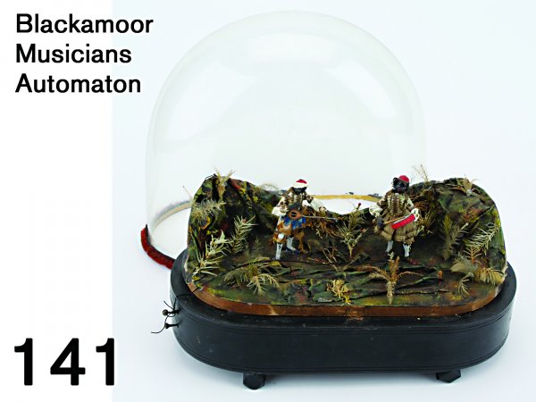 Blackamoor Musicians Automaton: a glass domed wooden base encloses mechanism and music box, 2 diminutive cloth and paper dressed musicians standing in a jungle like setting made of painted paper and feathers - one strums a lute whil