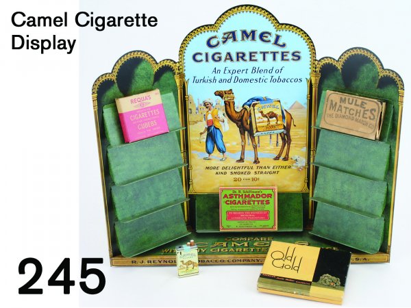 Camel Cigarette Display: lithographed tin display with colorful imagery; offered with several tobacco related products-Camel cigarette lighter, Old Gold Cigarette box, Requa's Medicated Cigarette box, Dr. R. Schiffmann's Asth
