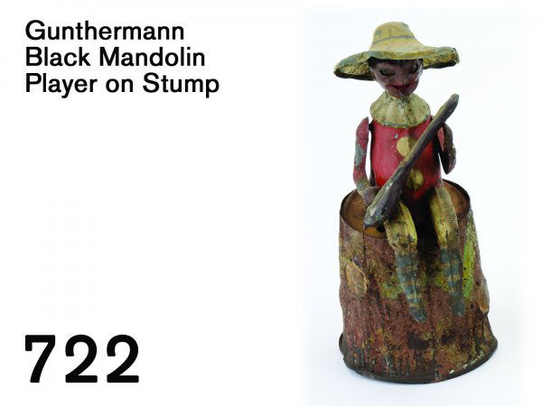 Gunthermann Black Mandolin Player on Stump: Gunthermann Black Mandolin Player on Stump painted tin figure in clown outfit with broad brim hat sits on tree stump which houses clockwork mechanism, he strums, moves eyes, and sticks out tongue - ac