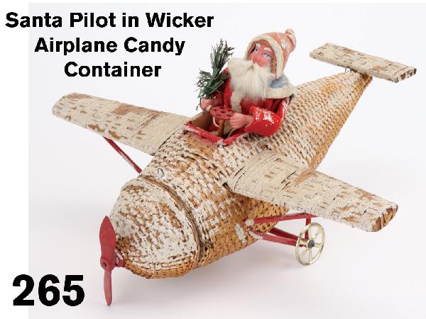 Santa Pilot in Wicker Airplane Candy Container: circa, 1915, very rare, exceptional example of a beautiful holiday item, cloth dressed painted composition Santa pilot holding feather tree sprig in monocoupe plane of wood and fine wicker with snow f