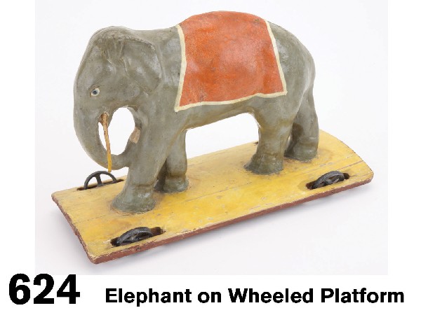 Elephant on Wheeled Platform: Painted papier mache elephant in gray with red blanket across back on yellow painted wood platform with 4 inset cast metal wheels, this delightful pull toy is from the Sonnenberg area of Germany circa